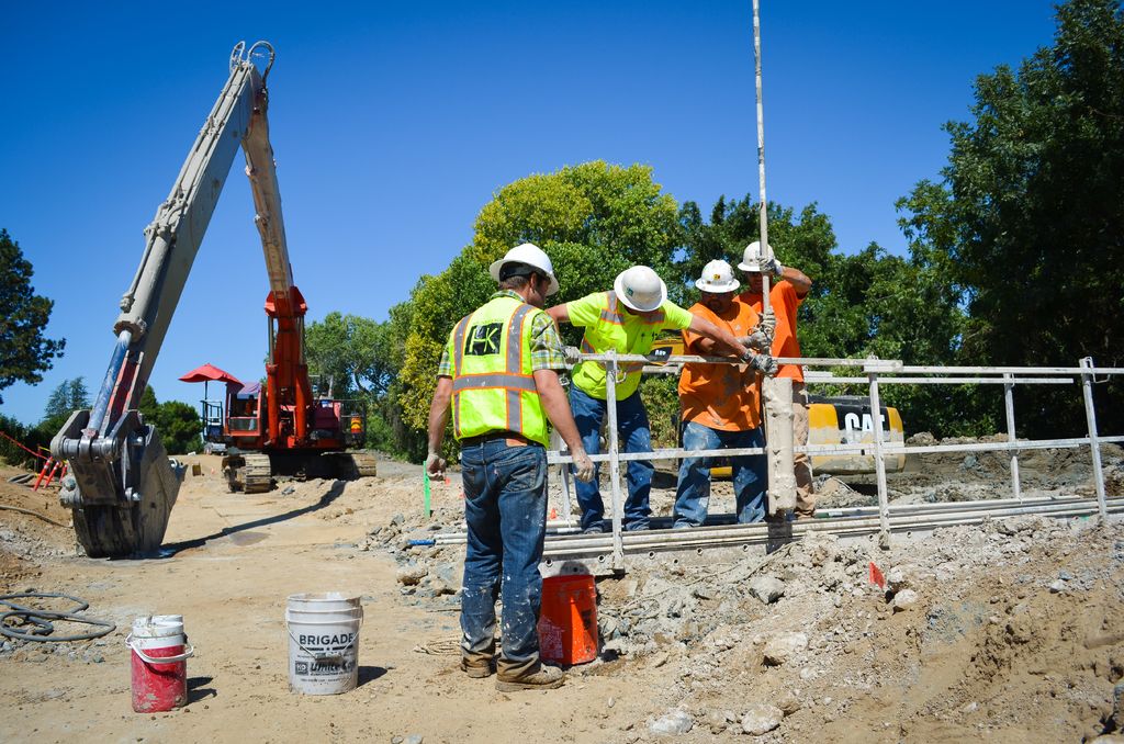 A construction crew in hard hats and safety vests working together on a job site