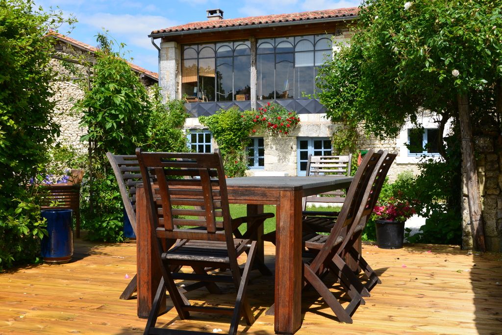 A wooden deck with an outdoor dining table in front of a vine-covered house