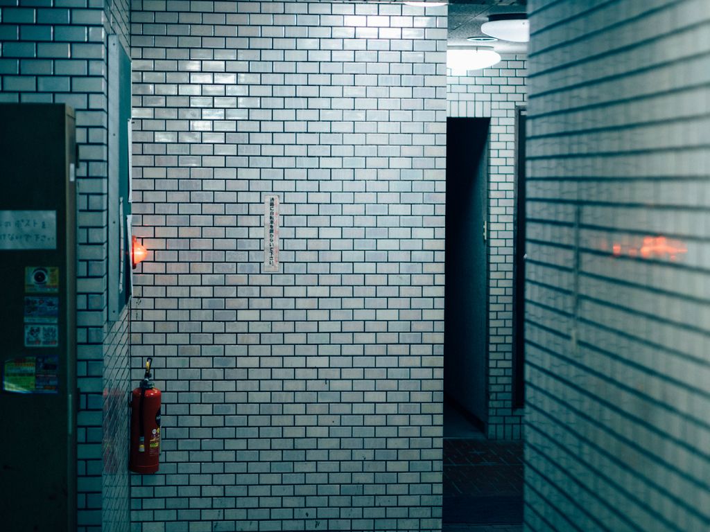 A red fire extinguisher mounted on a tiled hallway wall