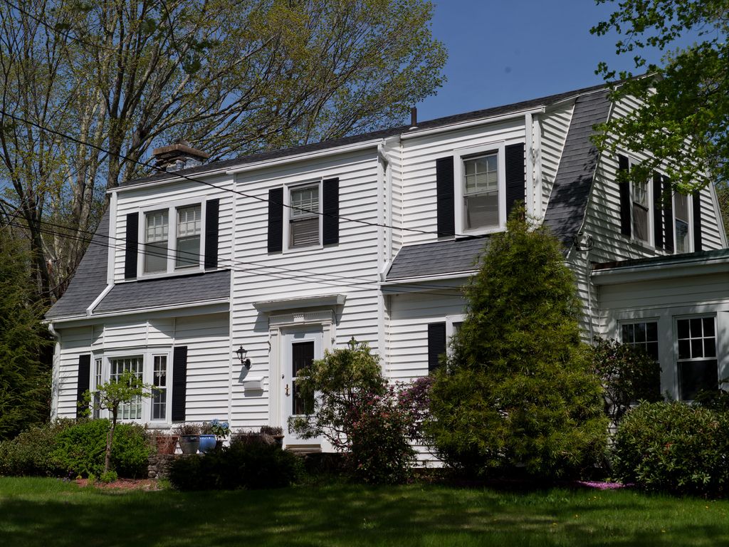A classic white two-story house with black shutters and a green lawn